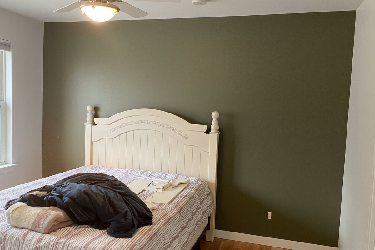A bedroom interior showing a bed with a white wooden headboard against a painted dark sage green wall, with a window, ceiling fan, and wood floor visible. The word 'After' appears in the lower left corner.